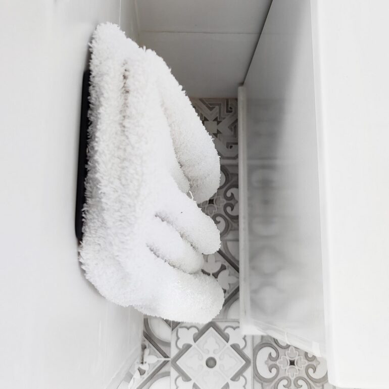 Gancho DOJO Mediano Muett instalado en pared de baño, diseño funcional moderno minimalista con toalla colgada