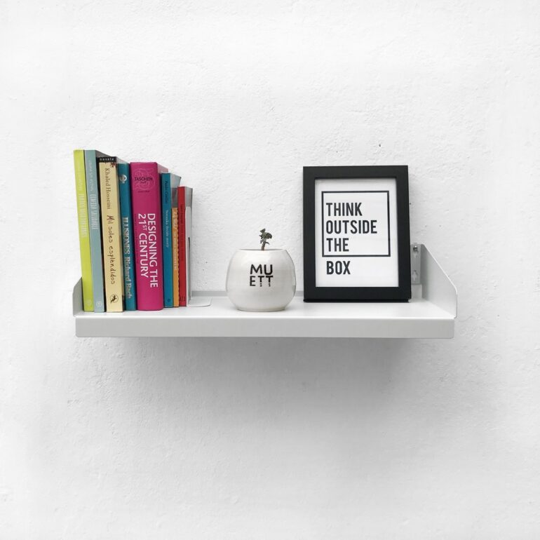 Estante FIT Muett blanco con objetos decorativos, cuadro, libros y maceta pequeña sobre fondo claro