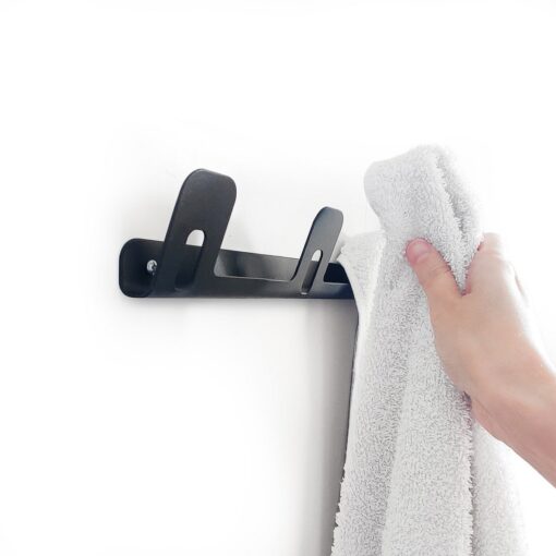 Mano colgando toalla en Perchero triple DOJO Muett negro diseño funcional moderno y minimalista