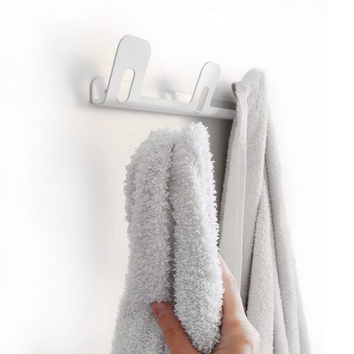 Mano colgando toalla en Perchero triple DOJO Muett blanco diseño funcional moderno y minimalista